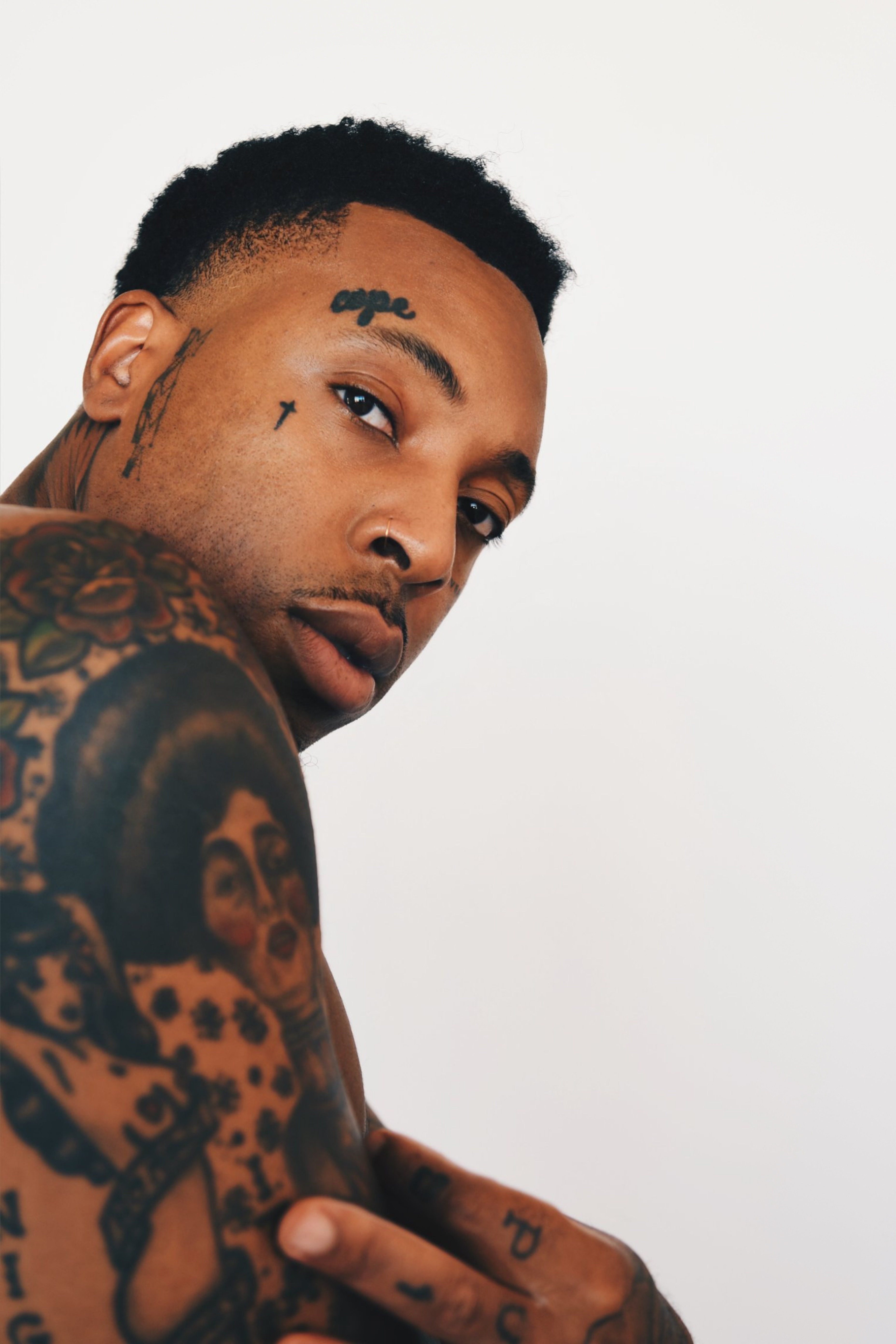 Singer-songwriter Obii poses for a portrait photograph, wearing a black turtleneck against a neutral background, looking directly at the camera with a contemplative expression. 